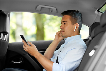 Image showing passenger with earphones and cellphone in taxi car