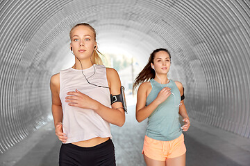 Image showing young women with earphones and smartphones running