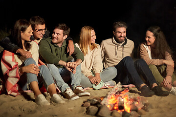 Image showing group of friends sitting at camp fire on beach