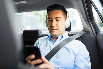 Image showing passenger with headphones using smartphone in car