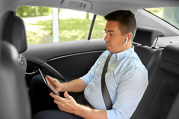 Image showing passenger with earphones and tablet pc in taxi car