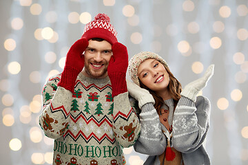 Image showing couple in ugly sweaters and mittens on christmas