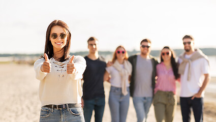 Image showing woman with friends on beach showing thumbs up