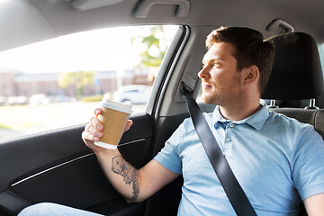 Image showing man with takeaway coffee on back seat of taxi car