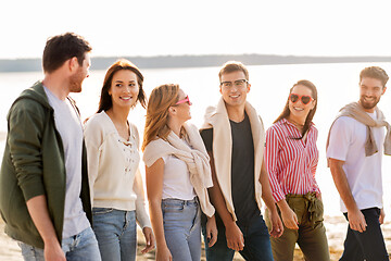 Image showing happy friends walking along summer beach