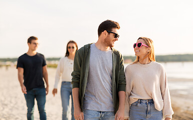 Image showing happy friends walking along summer beach