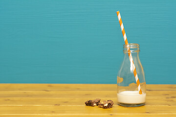 Image showing Straw and bottle half full of milk, and cookie crumbs