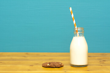 Image showing Milk and paper straw in a bottle with a cookie