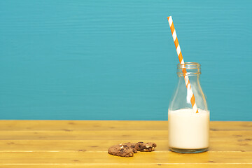 Image showing Straw and half full milk bottle with a half-eaten cookie