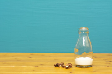 Image showing Glass bottle half full of milk with cookie crumbs