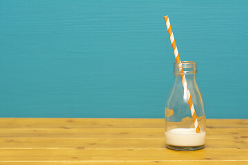 Image showing Glass bottle with dregs of milk with a paper straw