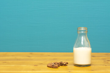 Image showing Half full milk bottle and a half-eaten chocolate cookie