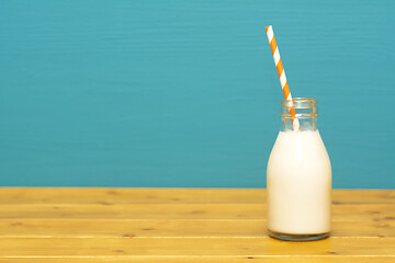 Image showing Fresh milk with a paper straw in a glass bottle