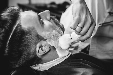 Image showing Client during beard shaving at barbershop.