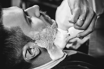 Image showing Client during beard shaving at barbershop.