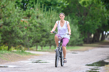 Image showing Girl riding a bicycle on a rainy warm summer morning