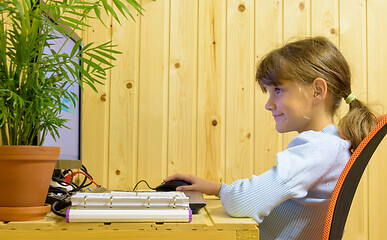 Image showing Happy girl takes online lessons at a computer in a country house