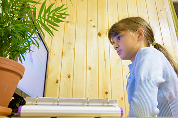 Image showing The student sits at the table in front of the monitor and carefully reads the task