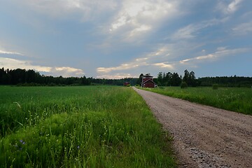 Image showing field, dirt road and two red barns in Finland