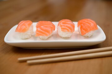 Image showing chopsticks and sushi with salmon on the mat