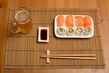 Image showing chopsticks, soy sauce, sushi and glass of beer on the mat