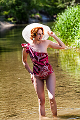 Image showing Red-haired woman standing in water on the beach