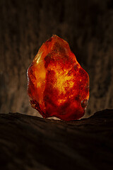 Image showing Beauty of natural raw amber. A piece of yellow and red semi transparent natural amber on piece of stoned wood.