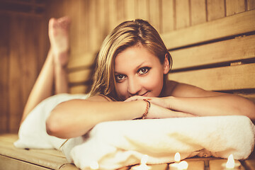 Image showing Lady relaxing in traditional wooden Finnish sauna.