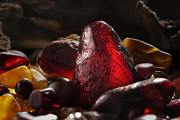 Image showing Beauty of natural amber. Several dark red natural amber stones in a cave.