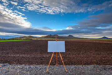 Image showing Blank art board and realistic wooden easel on the road. 