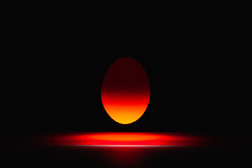 Image showing Red egg levitating over a black glass table 