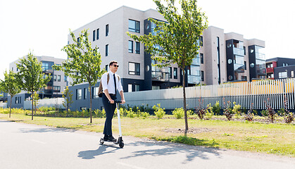 Image showing businessman with backpack riding electric scooter