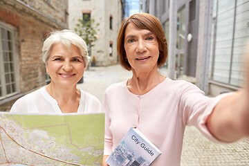 Image showing senior women with map and city guide taking selfie