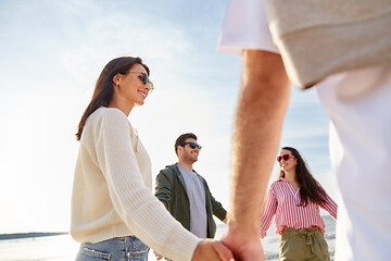 Image showing happy friends holding hands on summer beach