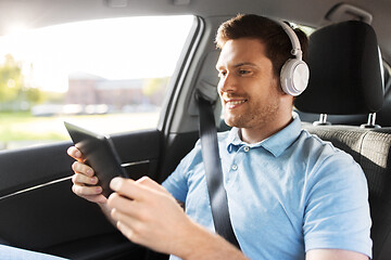 Image showing passenger in headphones with tablet pc in taxi car