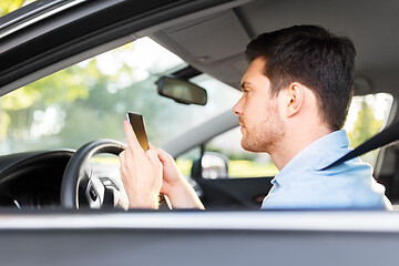 Image showing man driving car and using smartphone