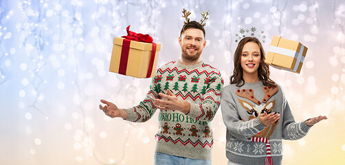 Image showing happy couple in christmas sweaters with gift boxes