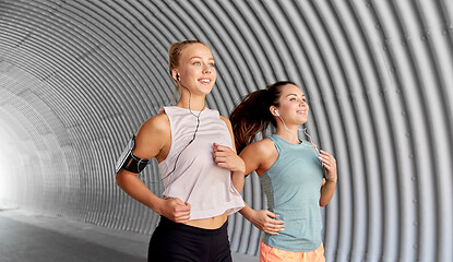 Image showing young women with earphones and smartphones running