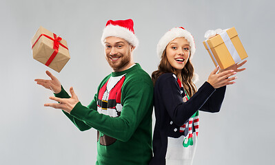 Image showing happy couple in christmas sweaters with gifts