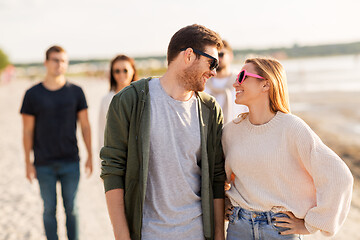 Image showing happy friends walking along summer beach