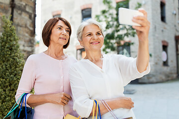 Image showing old women with shopping bags taking selfie in city