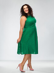 Image showing happy woman in green dress over grey background