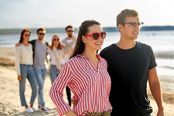 Image showing happy friends walking along summer beach