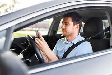 Image showing man driving car and using smartphone