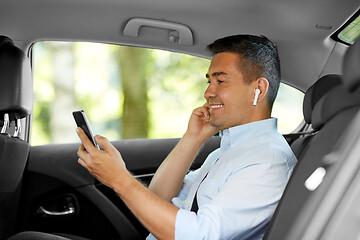 Image showing passenger with earphones and cellphone in taxi car