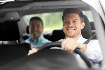 Image showing male taxi driver driving car with passenger