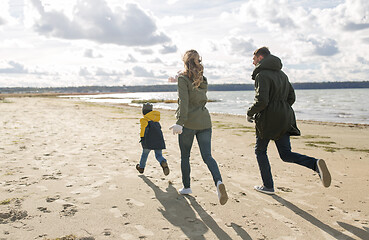 Image showing happy family running along autumn beach