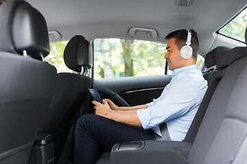 Image showing passenger with headphones using tablet pc in car