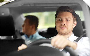 Image showing male taxi driver driving car with passenger