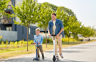 Image showing father and little son riding scooters in city